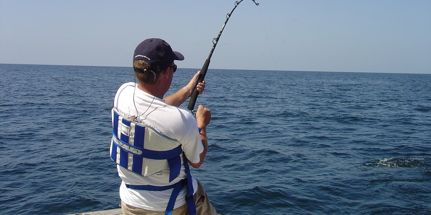 Man wearing a white shirt with gear attempting deep-sea fishing in the largest lake in Canada.